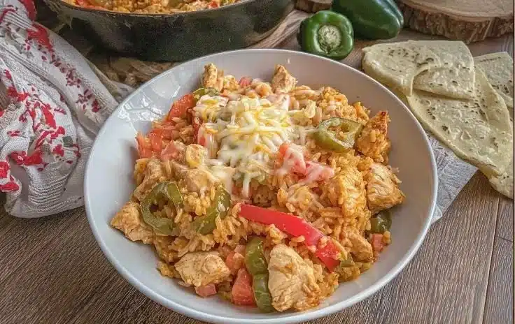 Creamy queso chicken fajita rice served in a pan, garnished with fresh ingredients.