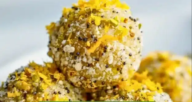 Lemon poppy seed energy bites on a textured surface with zest and poppy seeds.