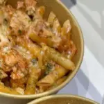 Baked chicken thigh pasta served with fresh herbs and vegetables