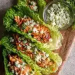 Buffalo Chicken Lettuce Wraps served on a plate with fresh vegetables and sauce.