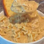 Bowl of creamy chicken alfredo soup garnished with parsley and parmesan cheese